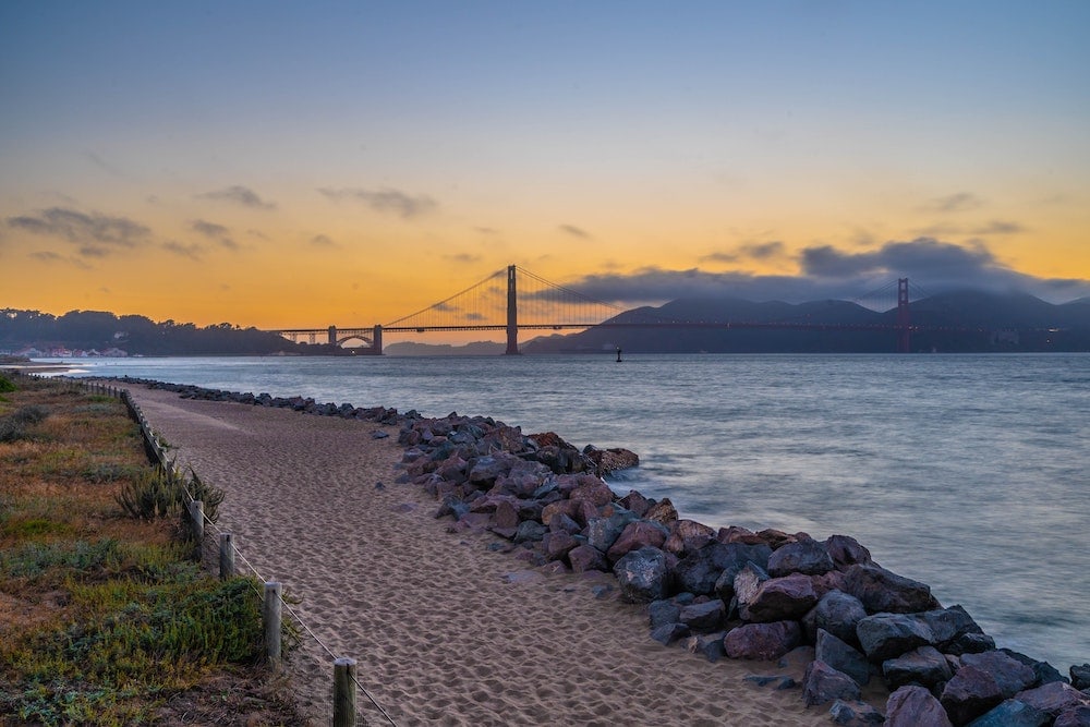 Crissy Field Beach view with the dog friendly sand up front and a sunset view of the Golden Gate Bridge in the background