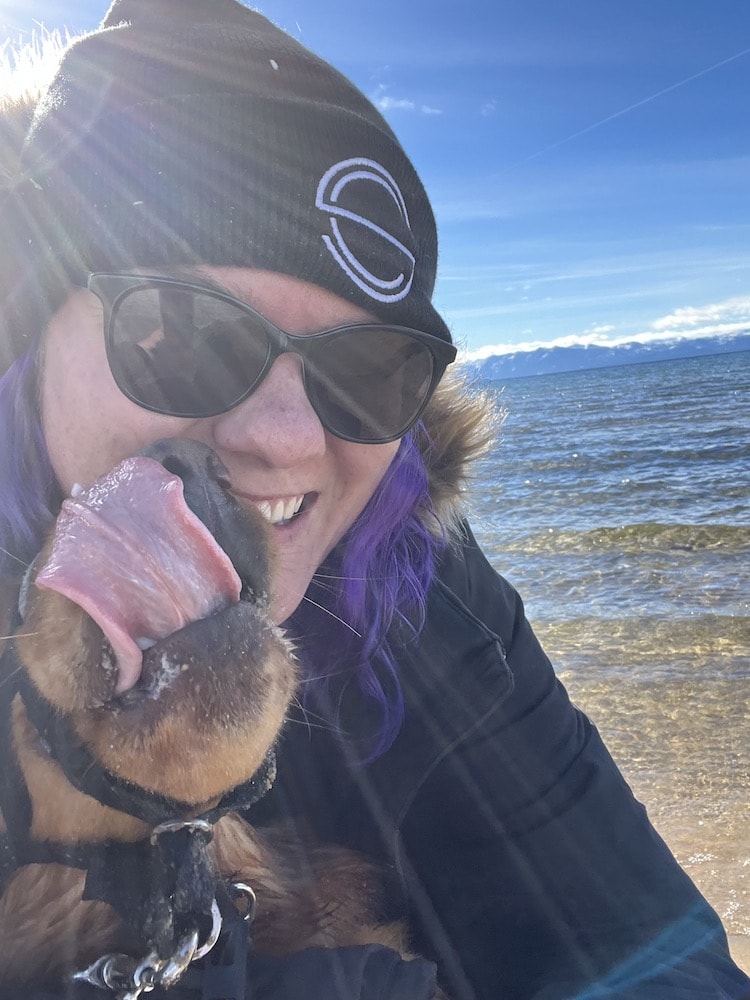 Nina and Theo laughing as he kissed her check at a beach in Tahoe