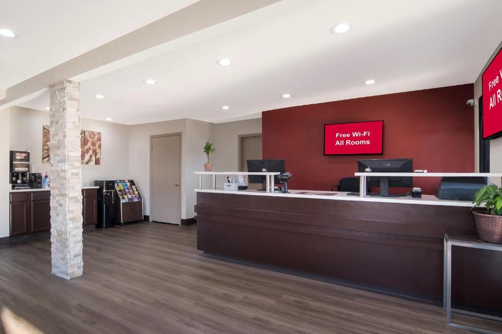 A reception desk with a sleek modern design. A monitor can also be seen with a photo that says FREE WI-FI ALL ROOMS. This is in Red Roof Inn Rocky Mount
