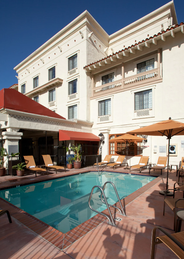 rectangular outdoor pool surrounded with lounge chairs. outside a white building with old design at Courtyard San Diego Old Town