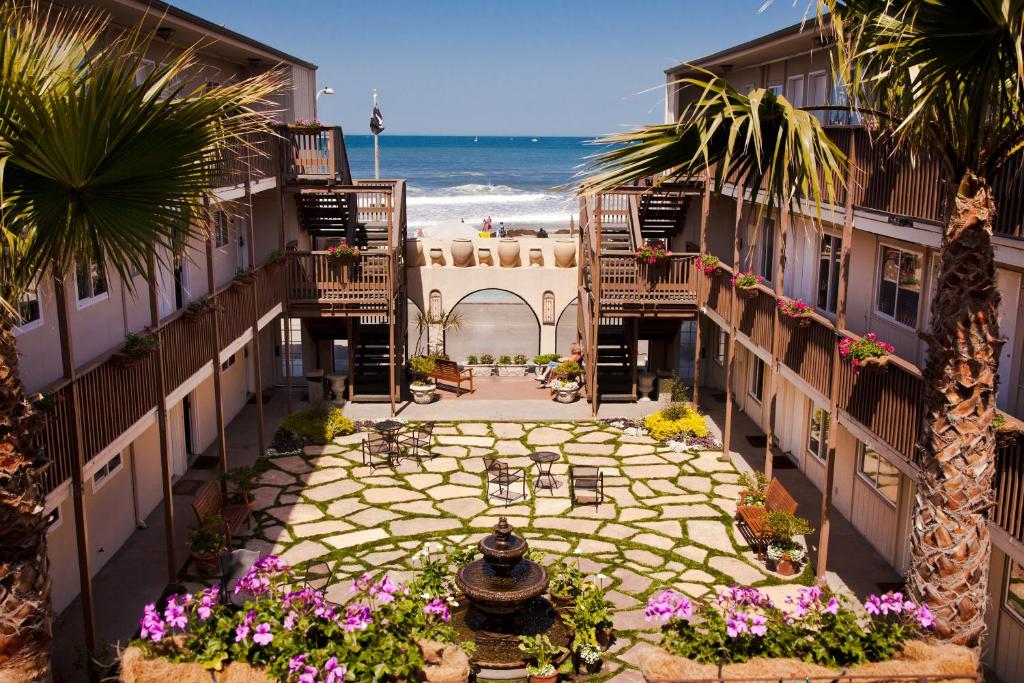 beautiful courtyard at Ocean Beach Hotel. the courtyard is in the middle of the hotel buildings. there is a fountain in the mddle surroundded with flowers and palm trees. A few steps from the courtyard is the beach.