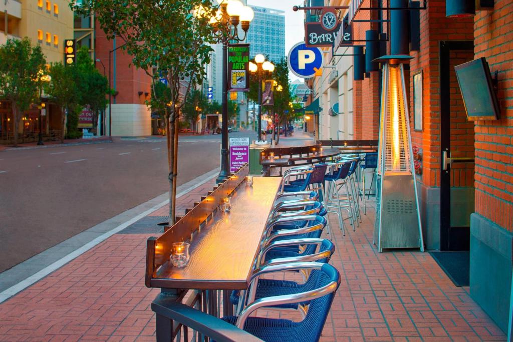 outdoor dining by the street at Residence Inn by Marriott San Diego Downtown/Gaslamp Quarter. there are blue high chairs facing the street infront of a brickwall building.