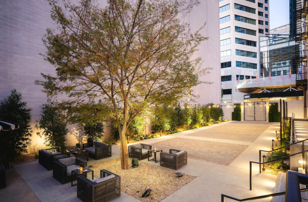 spacious inner courtyard at The Guild Hotel, a Tribute Portfolio Hotel by Marriott with lounge chairs on the side surrounding a tree.